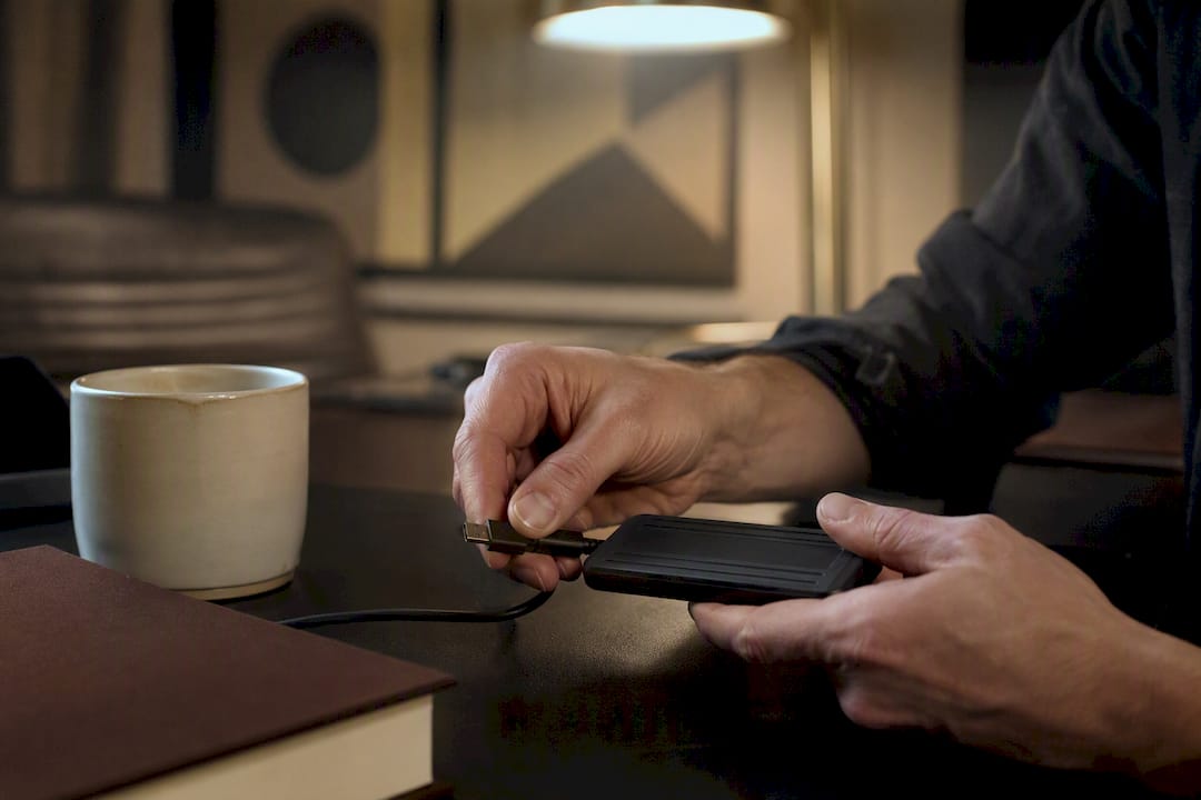 Hands connecting external drive cable in creative workspace