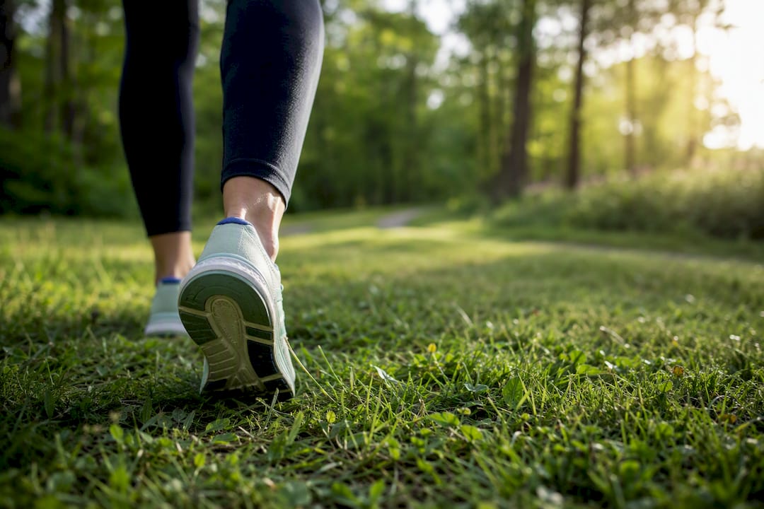 Feet walking on leafy nature trail in morning light