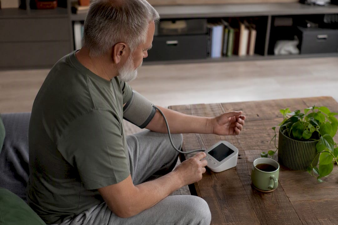 Elderly man measuring blood pressure at home