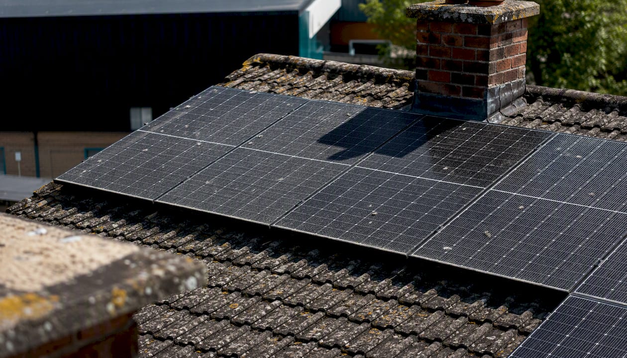 Shaded solar panels near chimney on residential roof