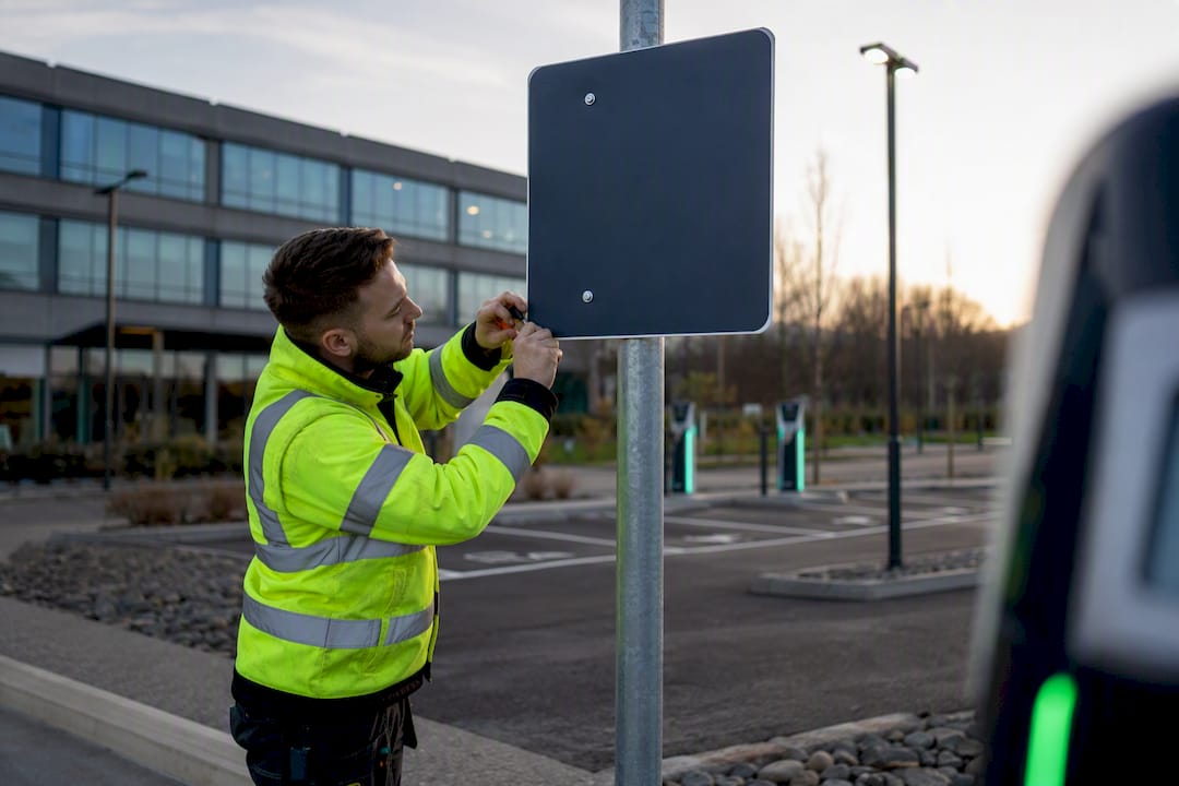 Technician installing EV charging sign at commercial site