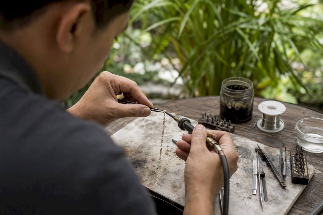 Hands using soldering iron on delicate jewelry joint