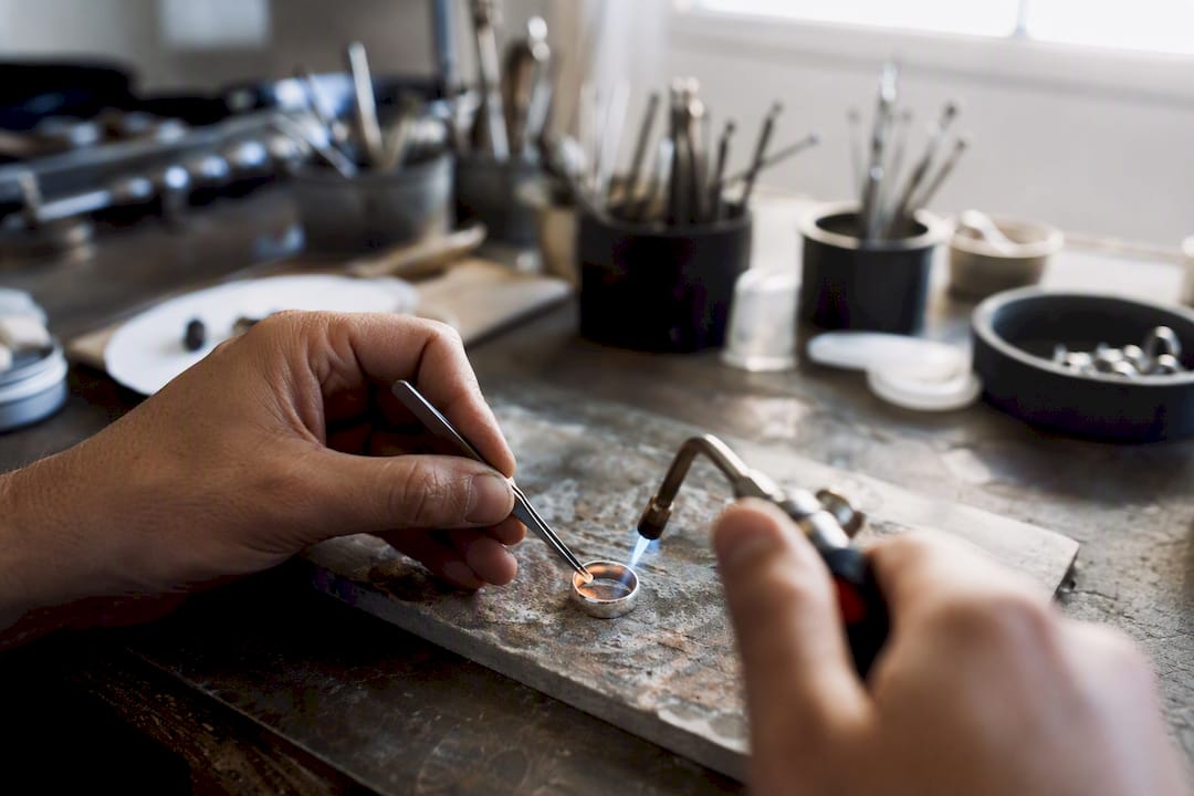 Jeweler heating silver jewelry joint with torch