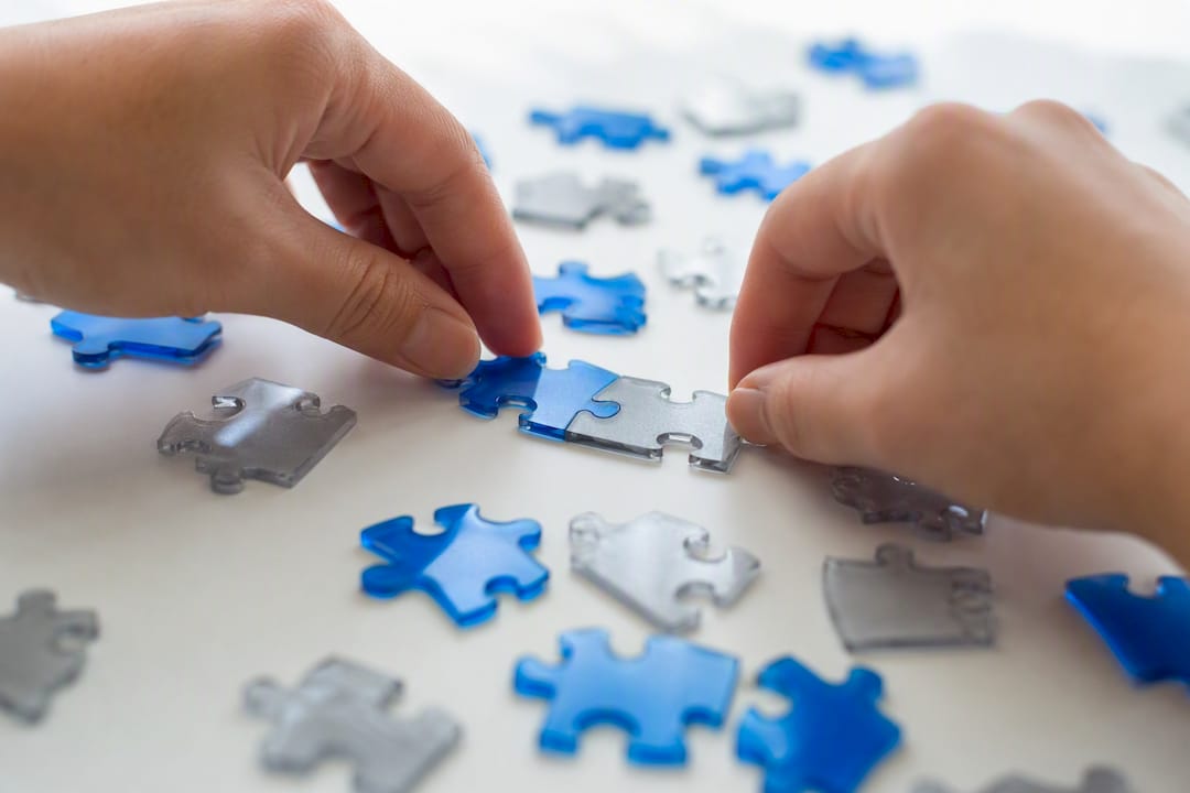 Hands assembling puzzle pieces on table