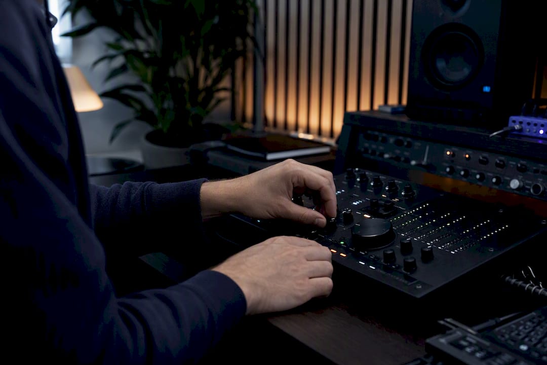 Producer hands adjusting mixing console knobs