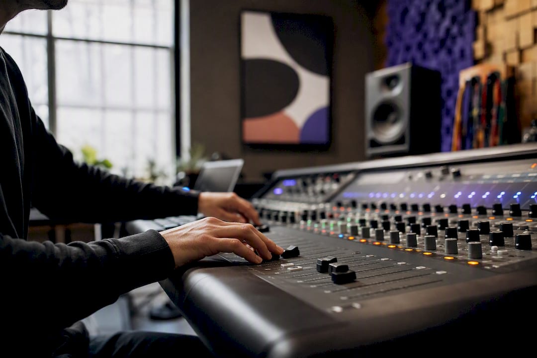 Producer adjusting mixing console controls