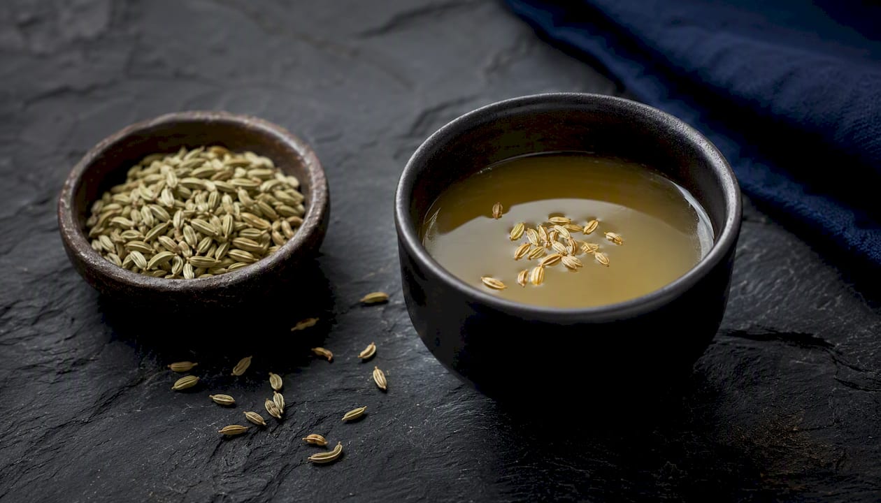 Cup of fennel tea beside wooden bowl of fennel seeds