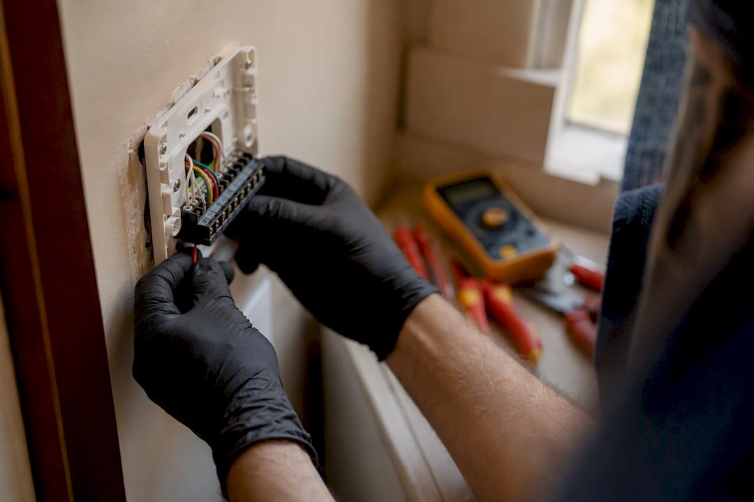 Technician inspecting thermostat wiring in utility closet