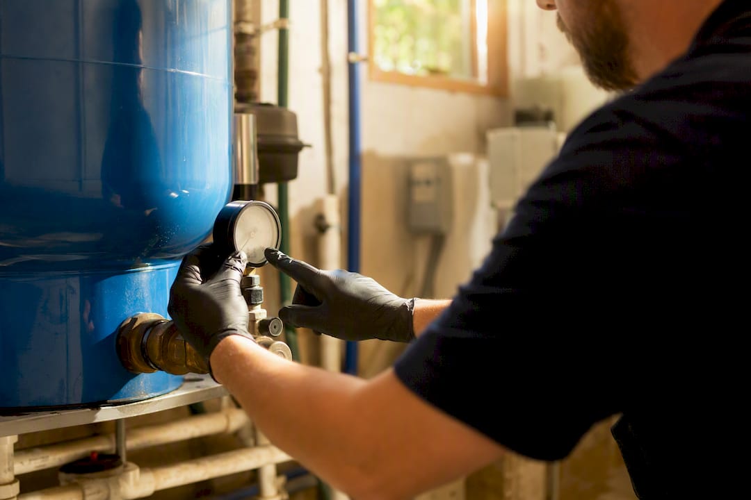 Hands inspecting pressure gauge on well tank
