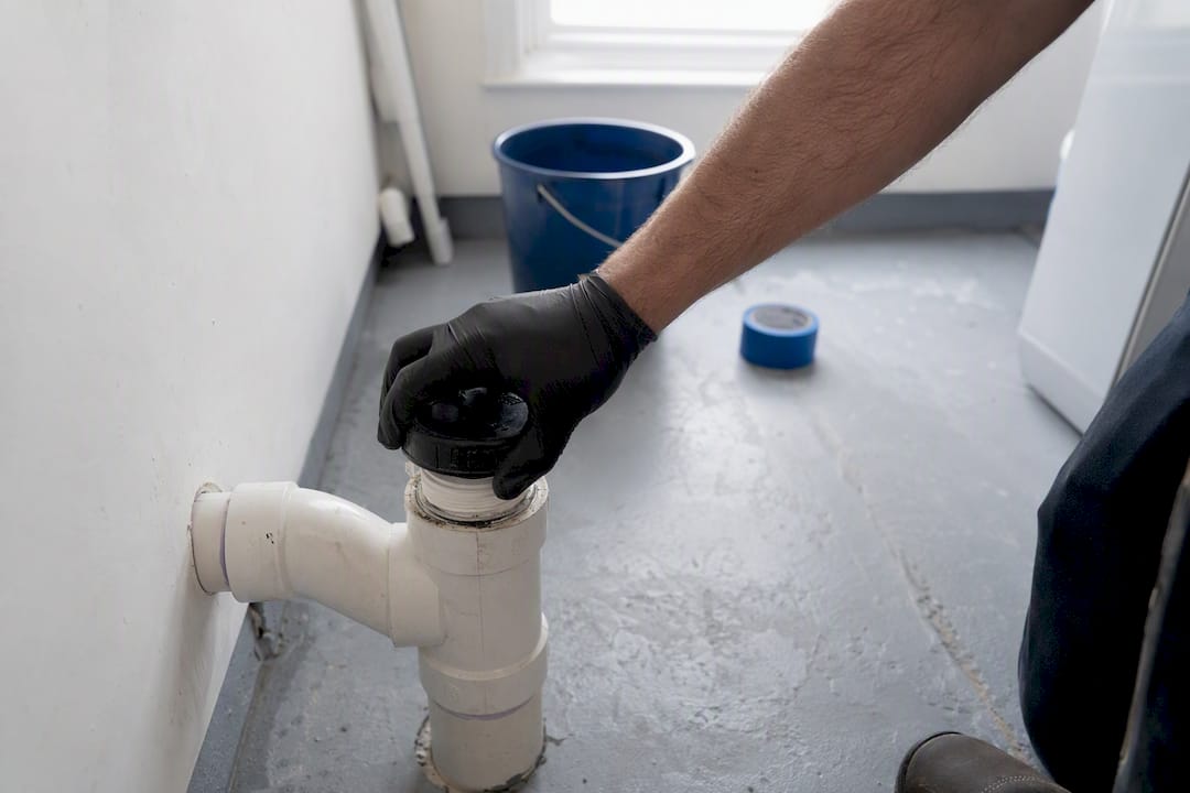 Gloved hand opening indoor sewer cleanout cap