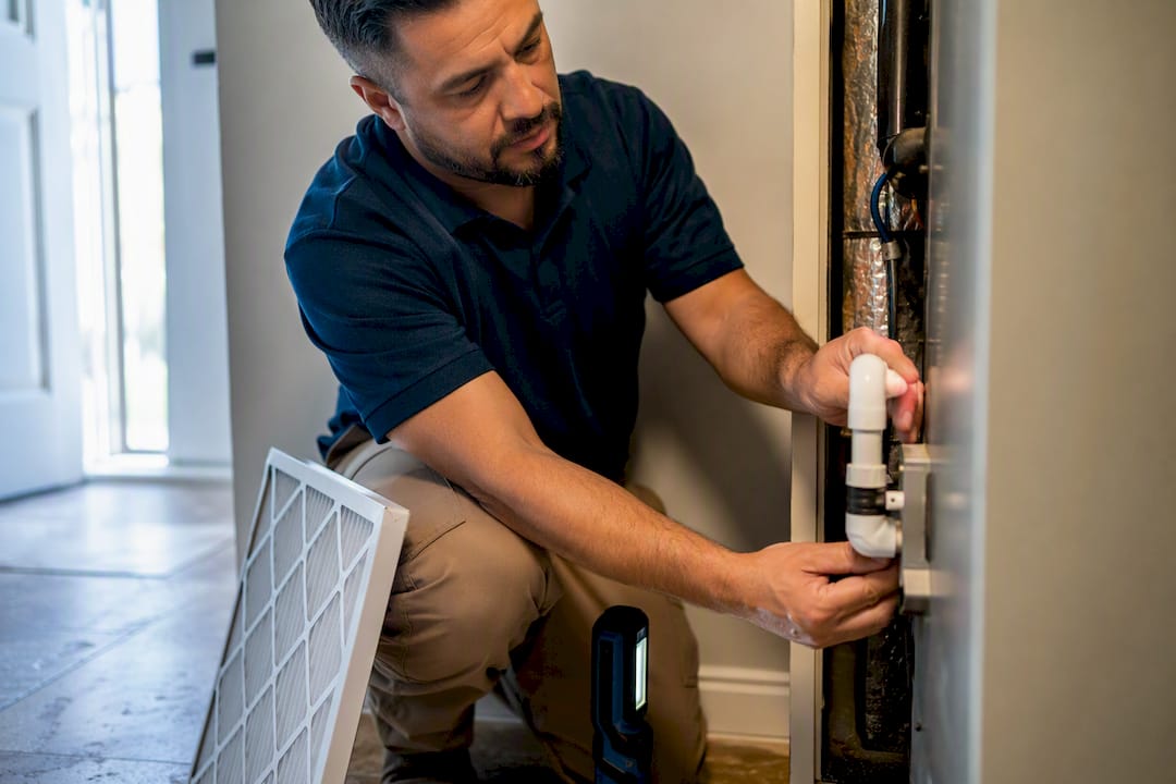 Technician inspecting an HVAC condensate drain