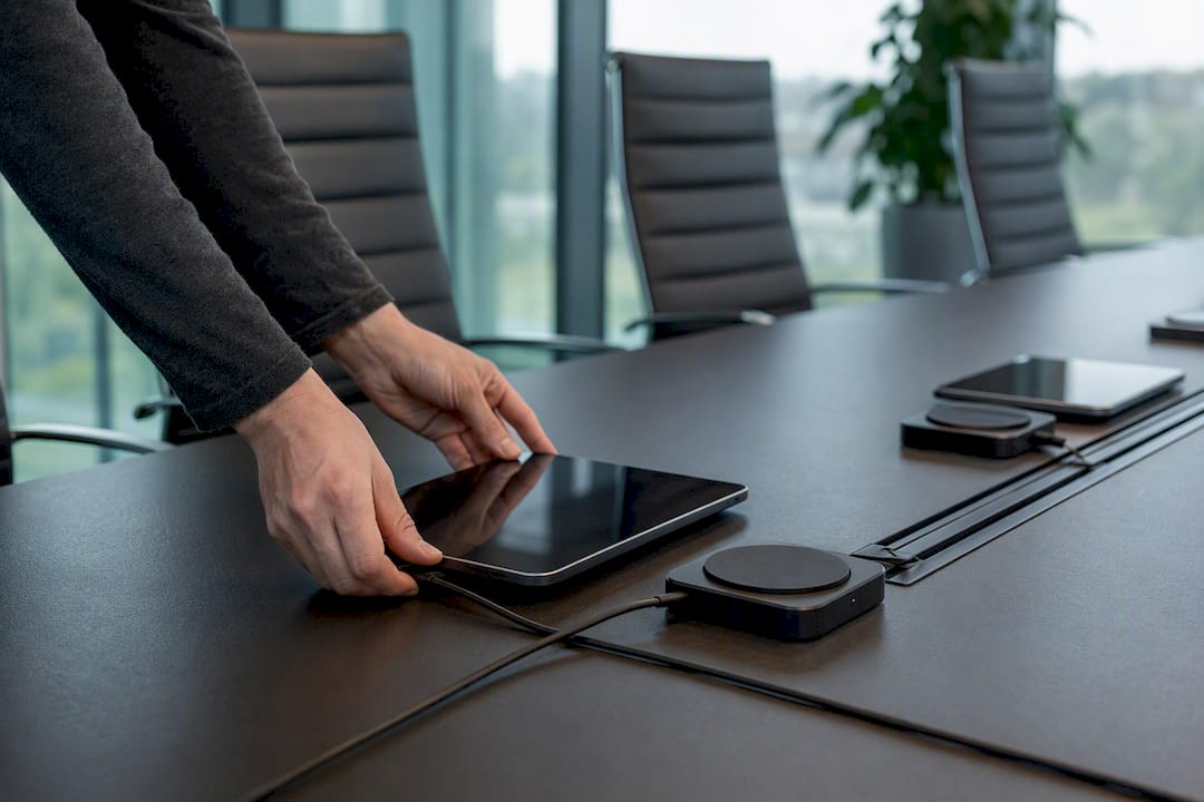 Hands setting up digital devices in meeting space
