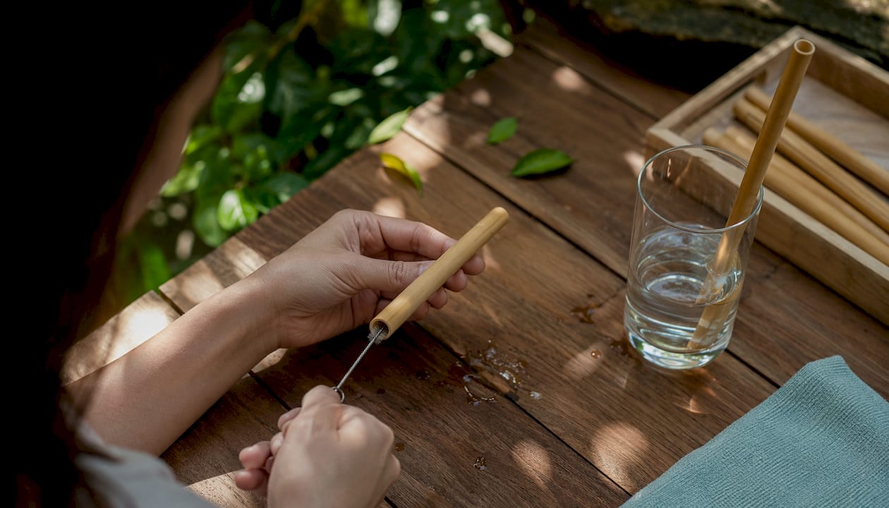 Hands cleaning bamboo straw by sink