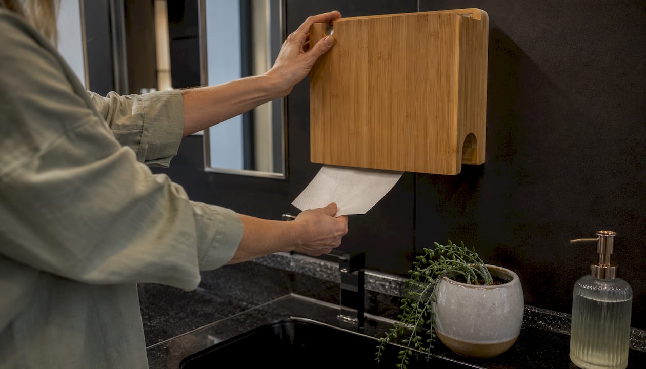 Hands pulling sheet from bamboo dispenser