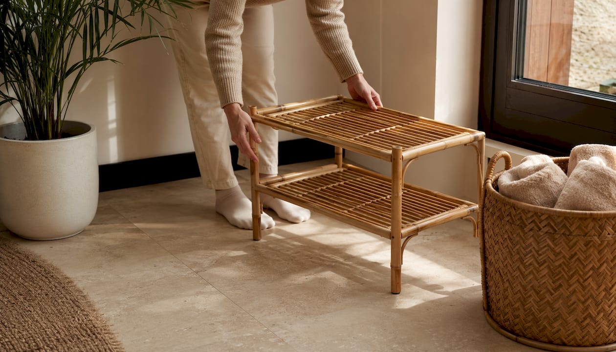 Hands unfolding bamboo luggage rack on wooden floor