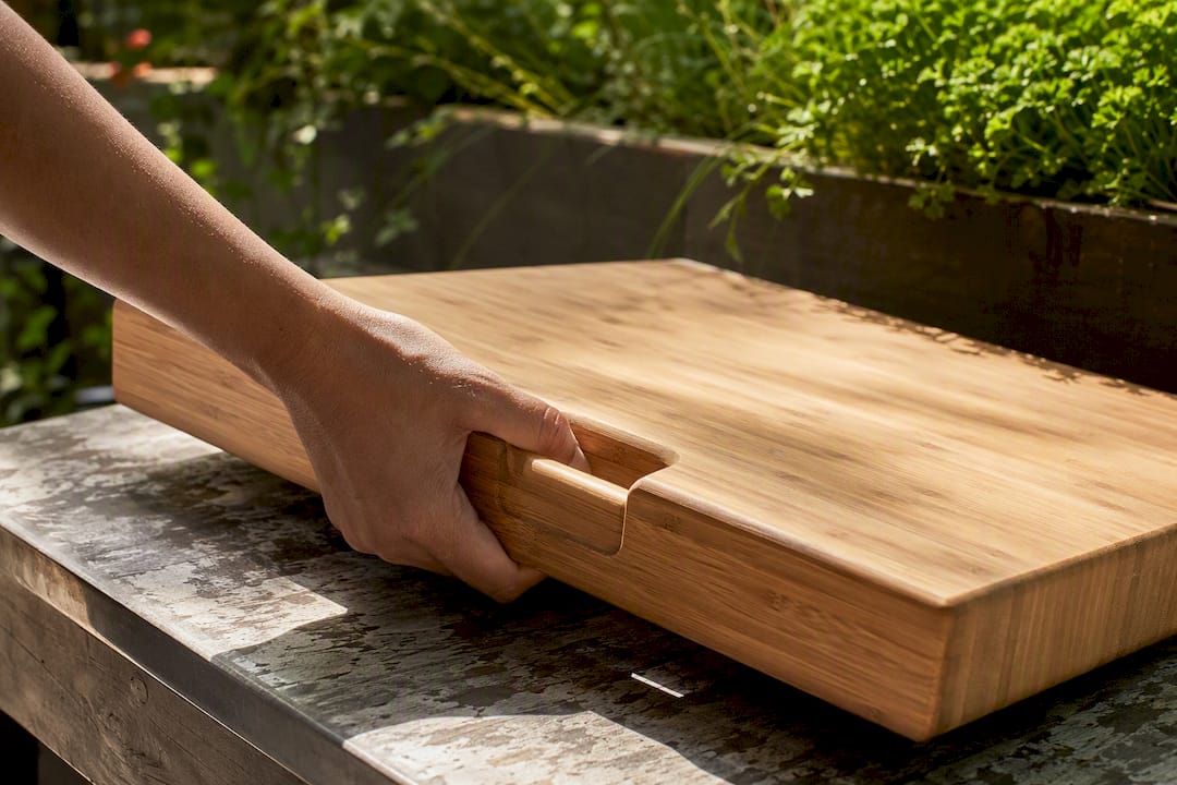 Hand lifting large bamboo cutting board by handle