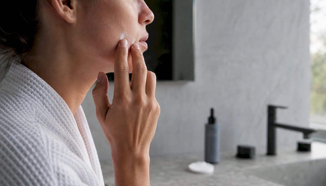 Gently applying cream to hands after the skin has fully recovered from microneedling.