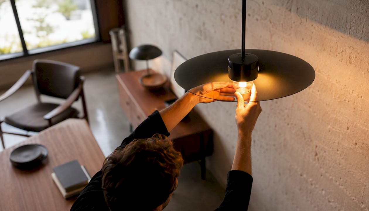 Hands installing warm LED bulb in interior fixture