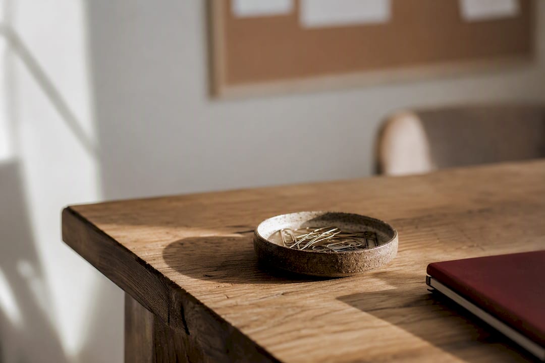 Table corner with bowl of paperclips and mug