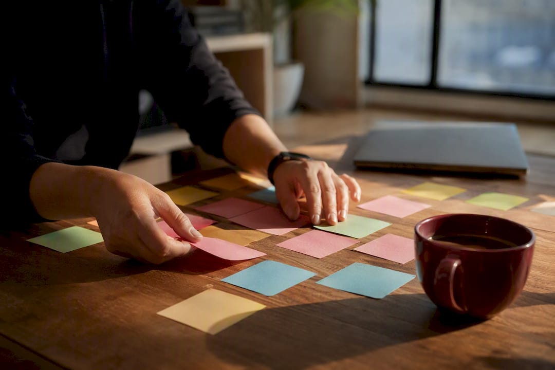 Hands arranging sticky notes on corkboard