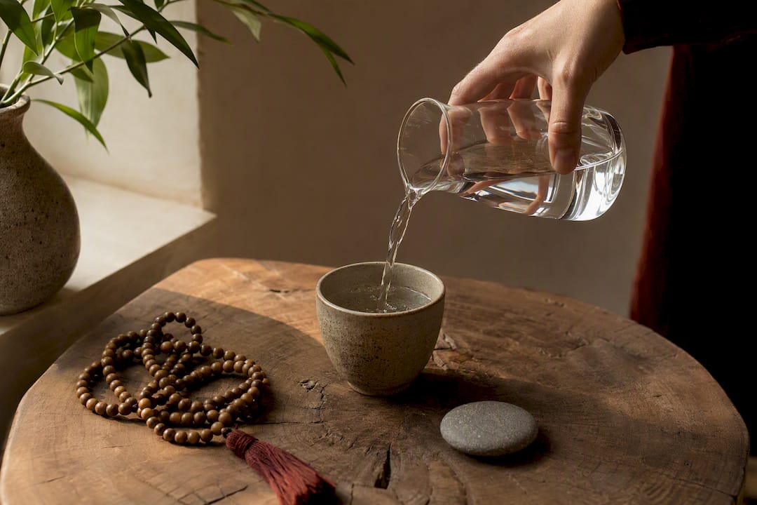 Pouring water into a ceramic cup on desk