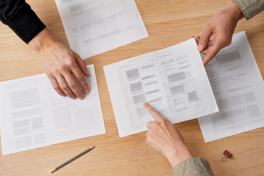 Hands reviewing rough printed design layouts