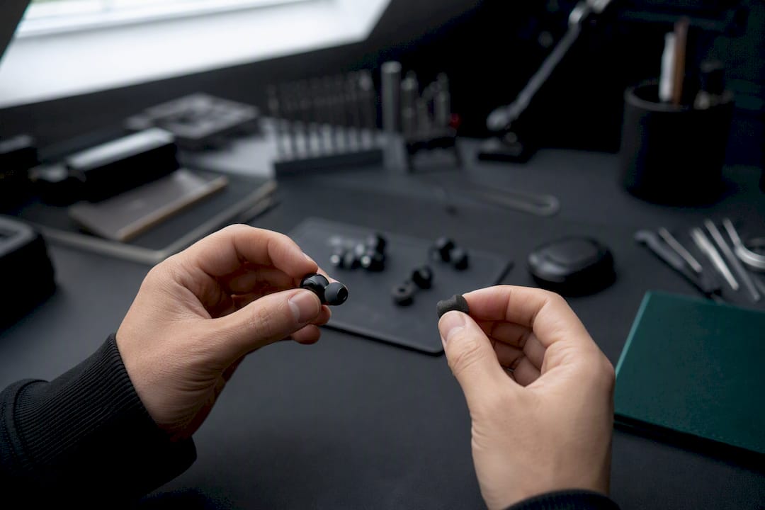 Hands removing silicone and foam earbud tips differently