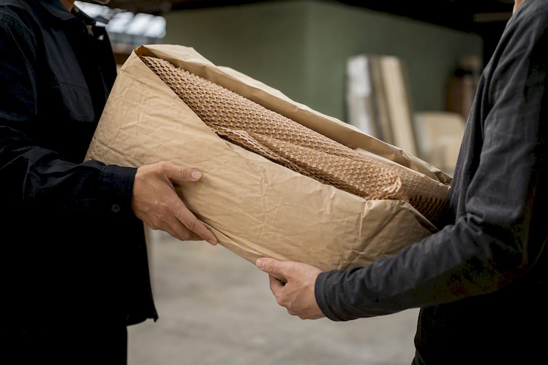 Hands passing wrapped furniture parcel