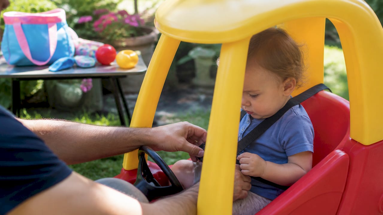 Hands buckling toddler car seat in kitchen