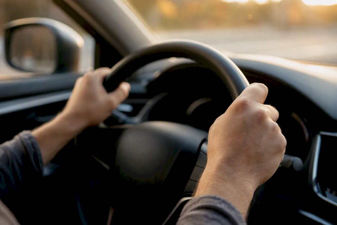 Close-up of hands gripping steering wheel anxiously