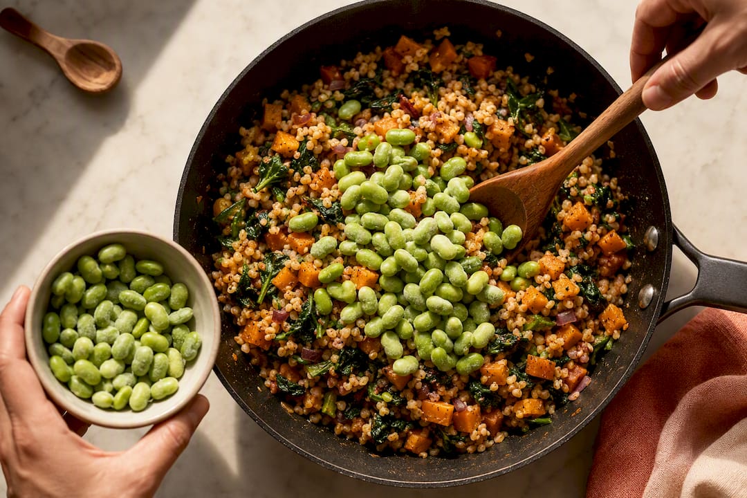 Hands adding edamame to a grain dinner