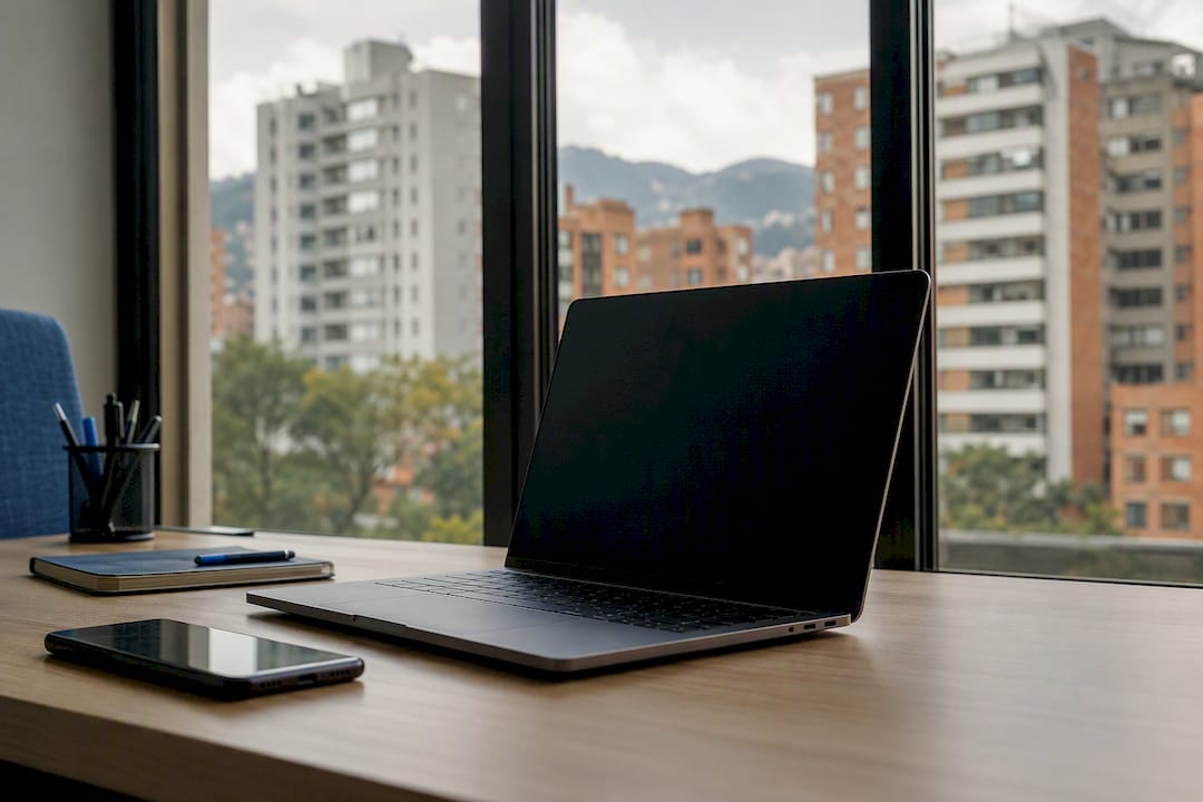 La pantalla del portátil apagada, con vistas a los edificios de la ciudad a través de la ventana.