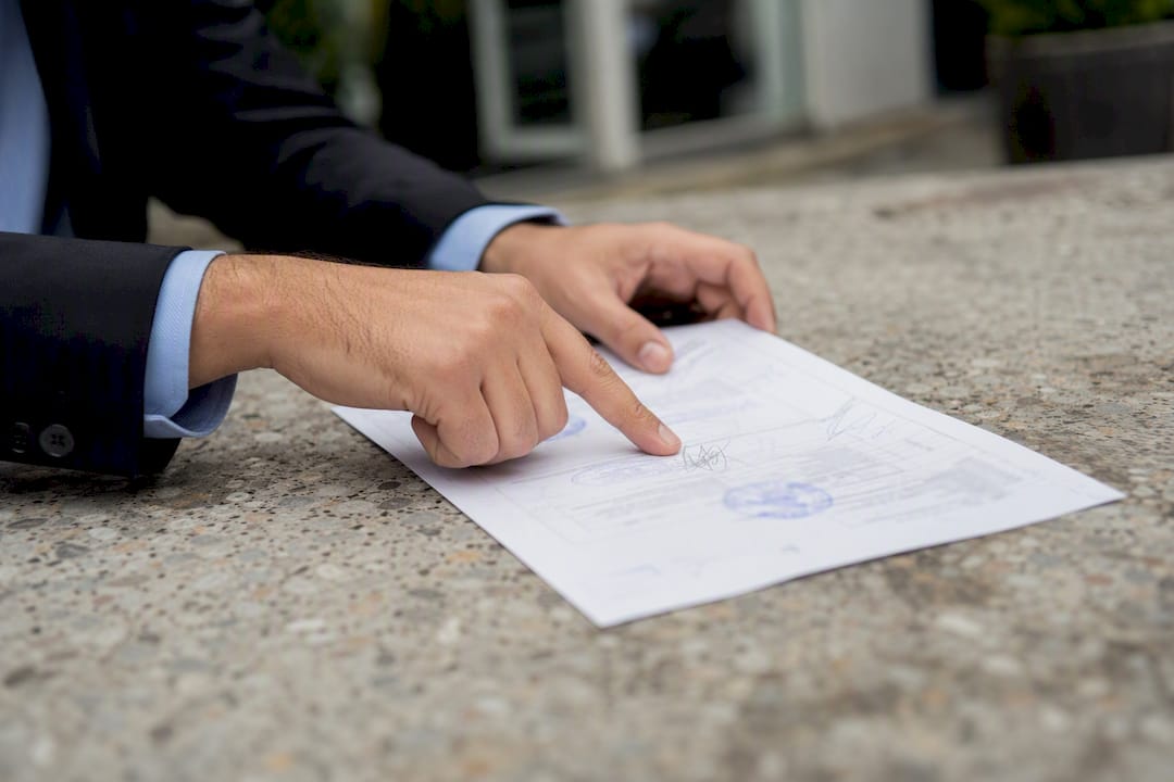 Manos de un abogado señalando anotaciones en un certificado