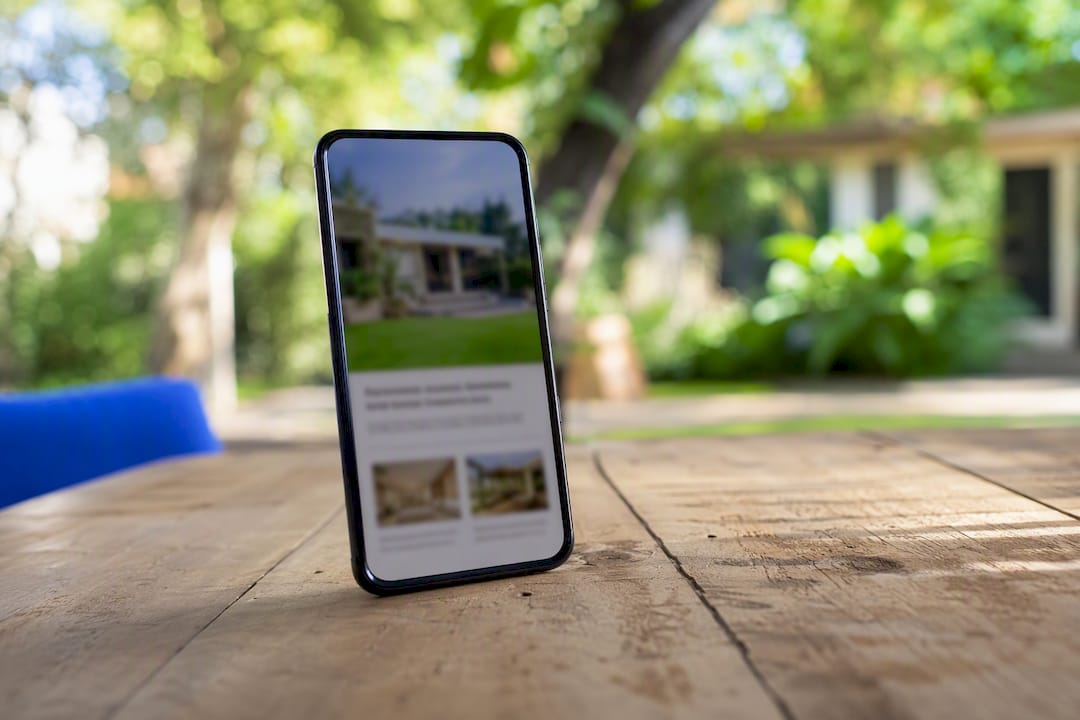 Mano sosteniendo un smartphone con borrador de anuncio de finca