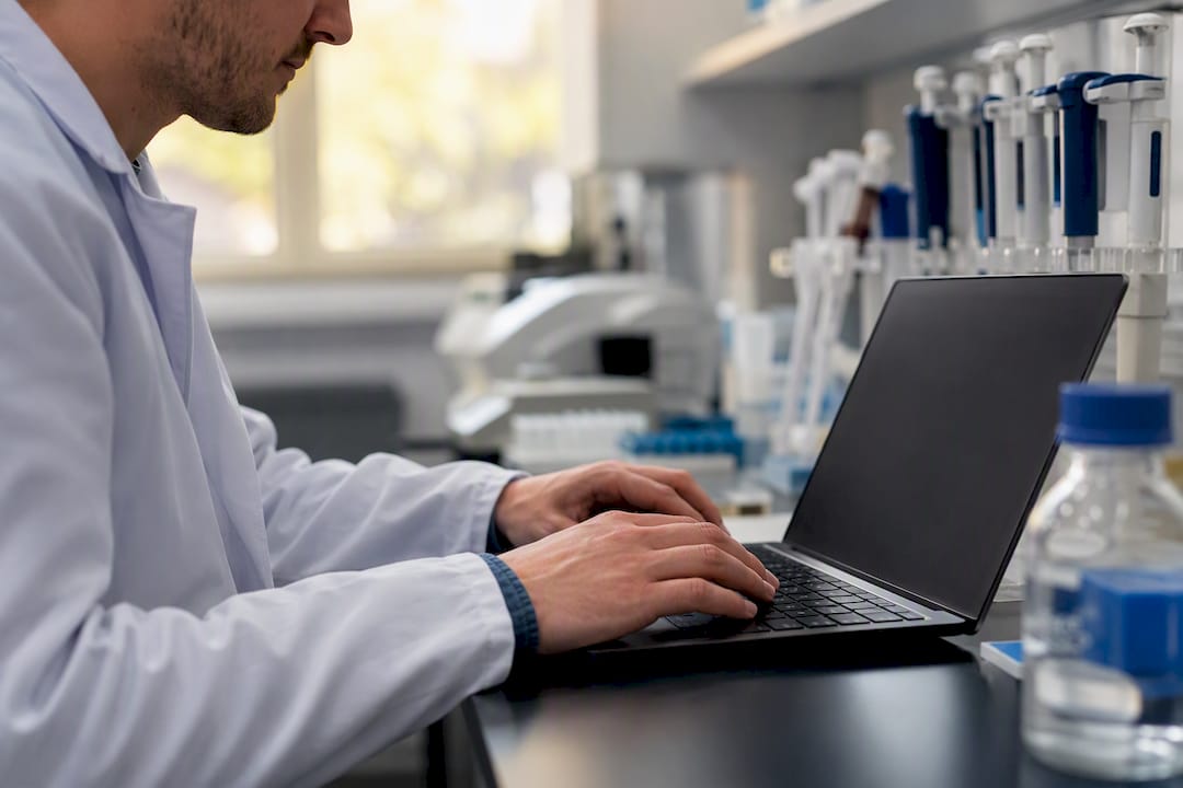 Hands registering antibody data on laptop
