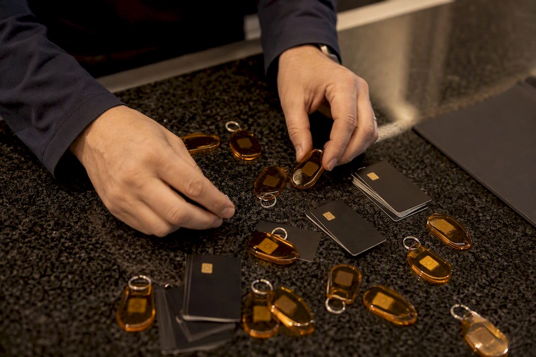Hands handling amber security tokens on dark desk