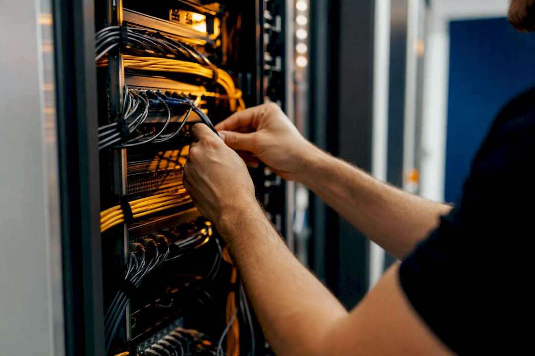 Hands inspecting server rack cables in data center