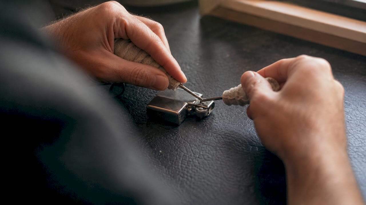 Hands adjusting lighter hinge with screwdrivers