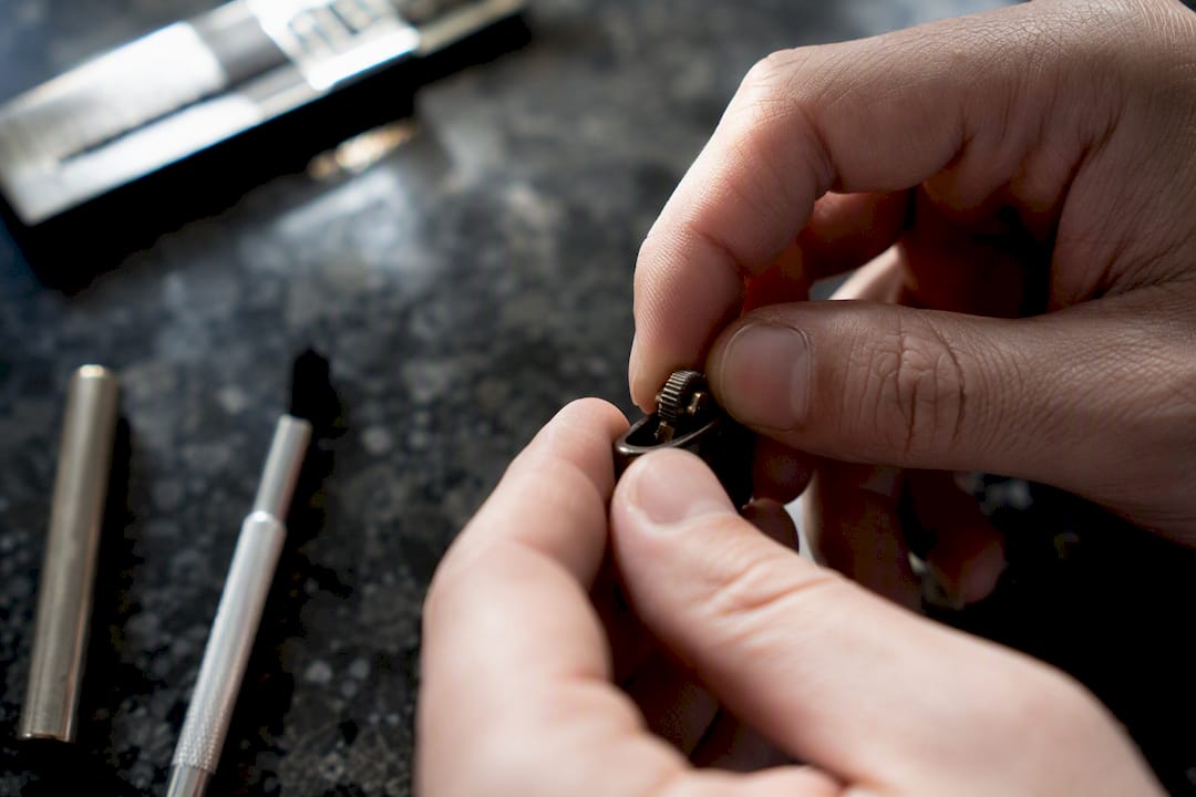 Hands inspecting lighter striker wheel