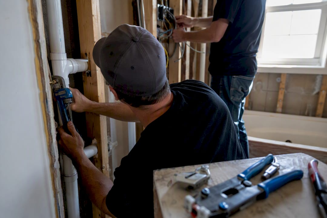 Hands installing plumbing and electrical wiring during renovation