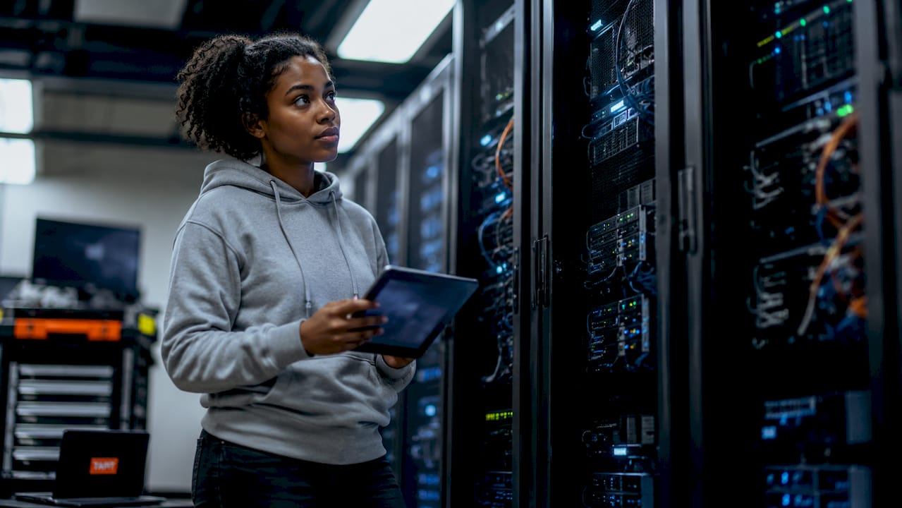Engineer reviewing device telemetry on tablet in server room