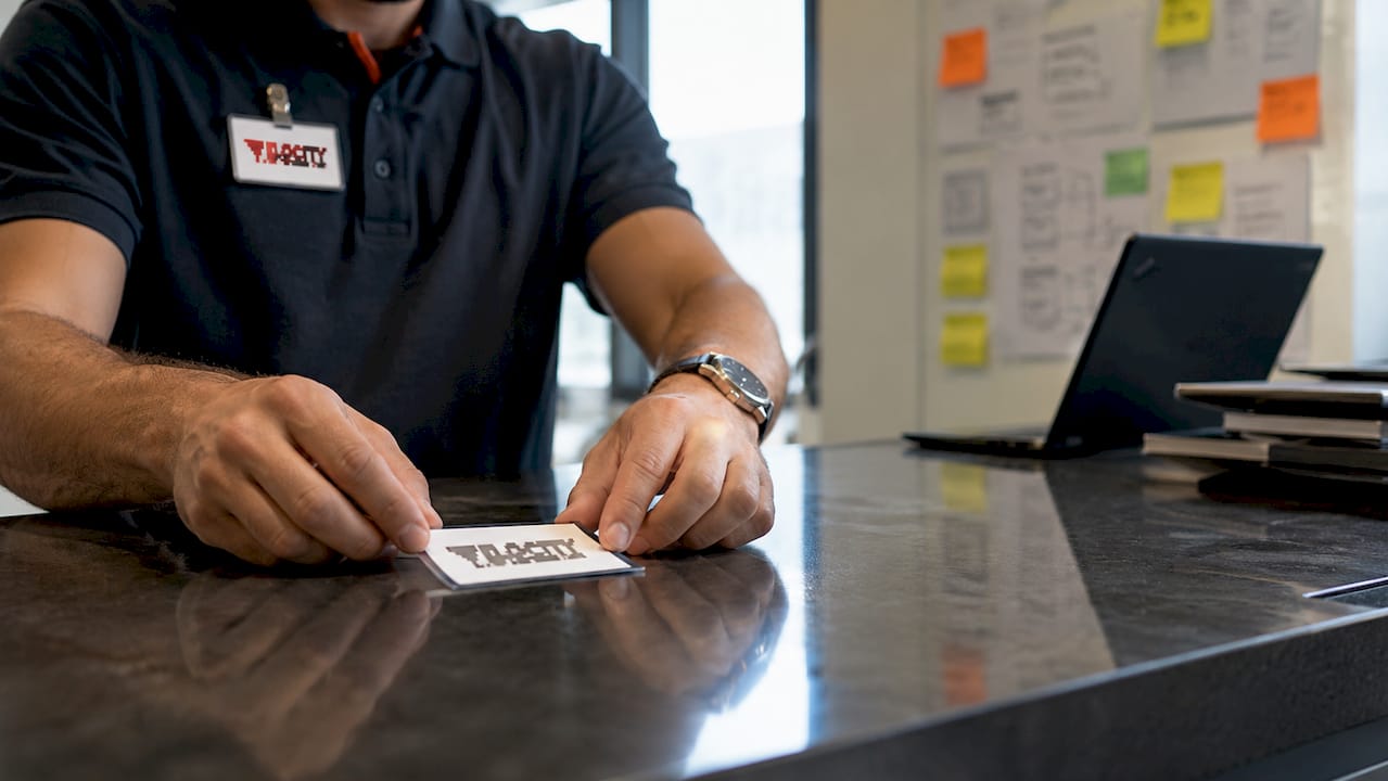 Hands holding physical ticket near IT kiosk