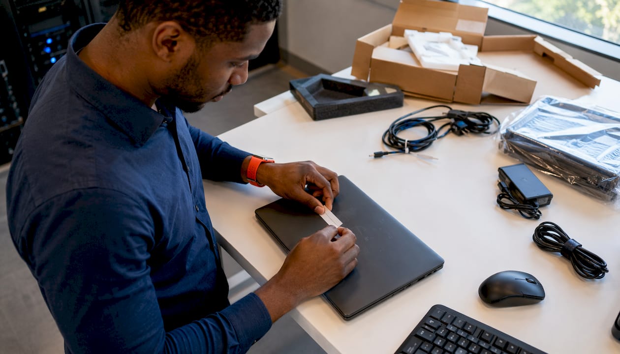 Technician tagging laptop for deployment