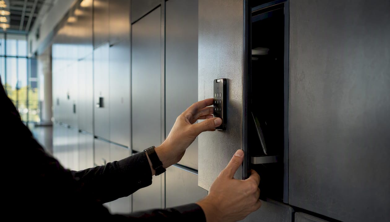 Hands unlocking IT device locker in office corridor