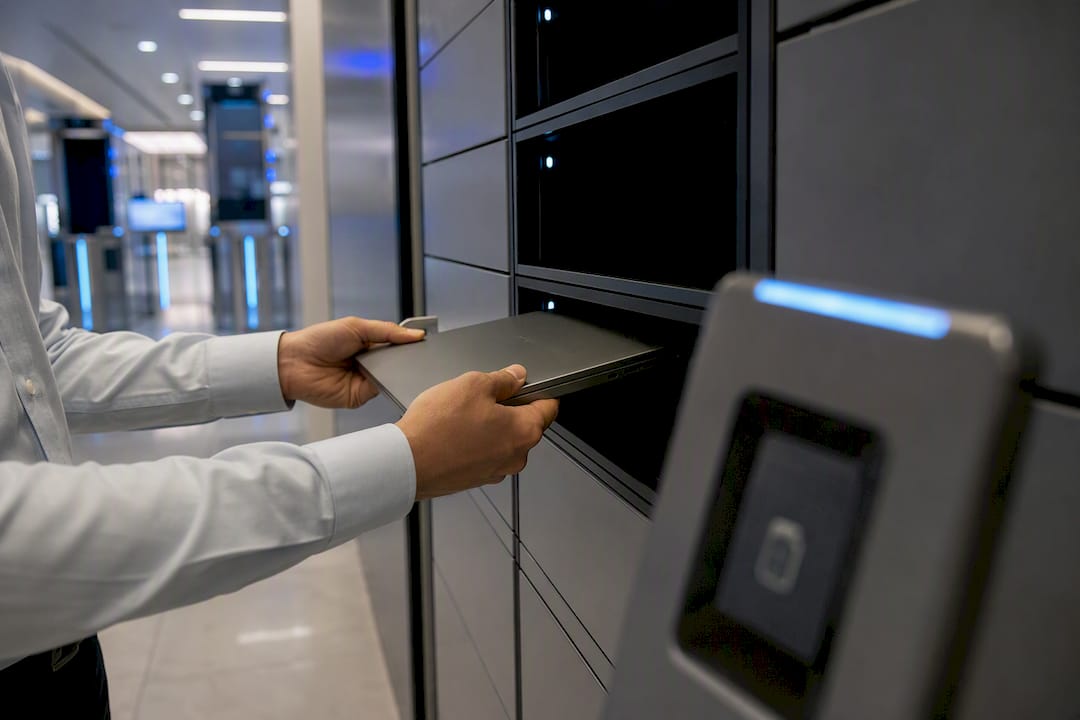 Hands placing laptop into secure IT locker