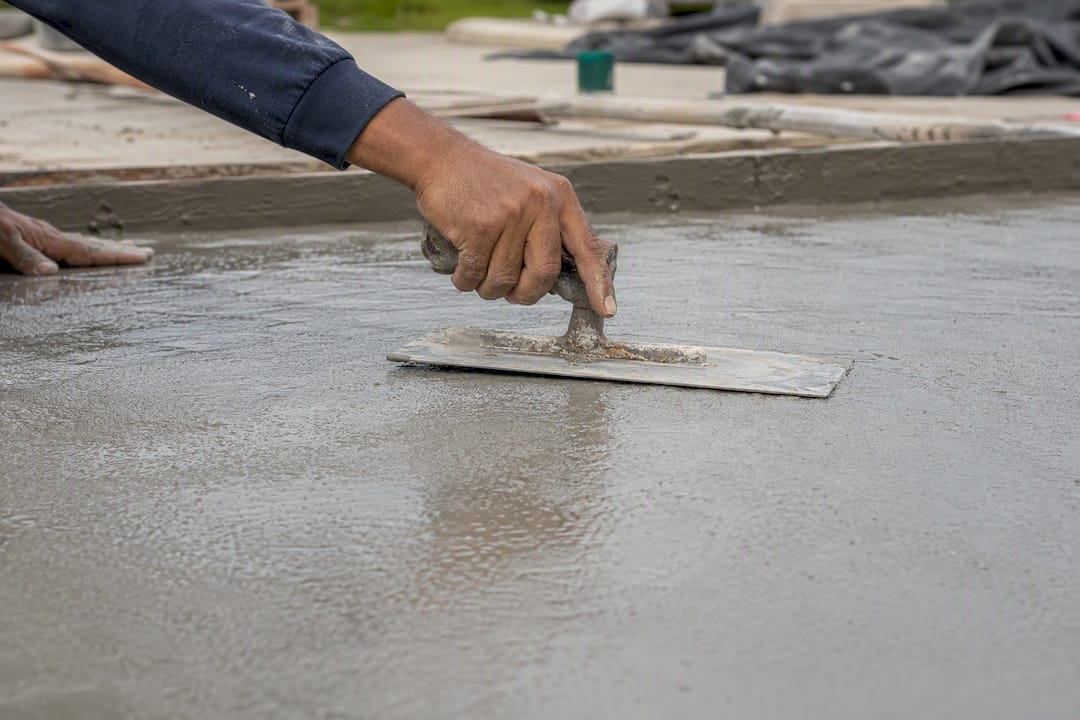 Hands broom-finishing fresh concrete driveway