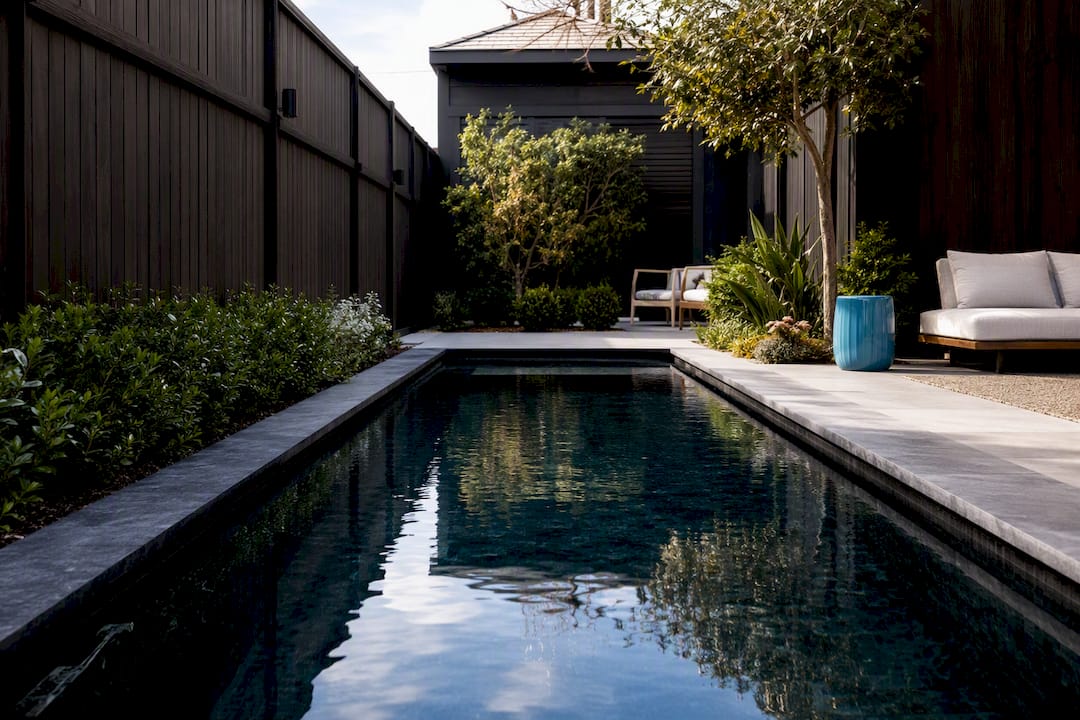 Dark fence receding beside reflective pool