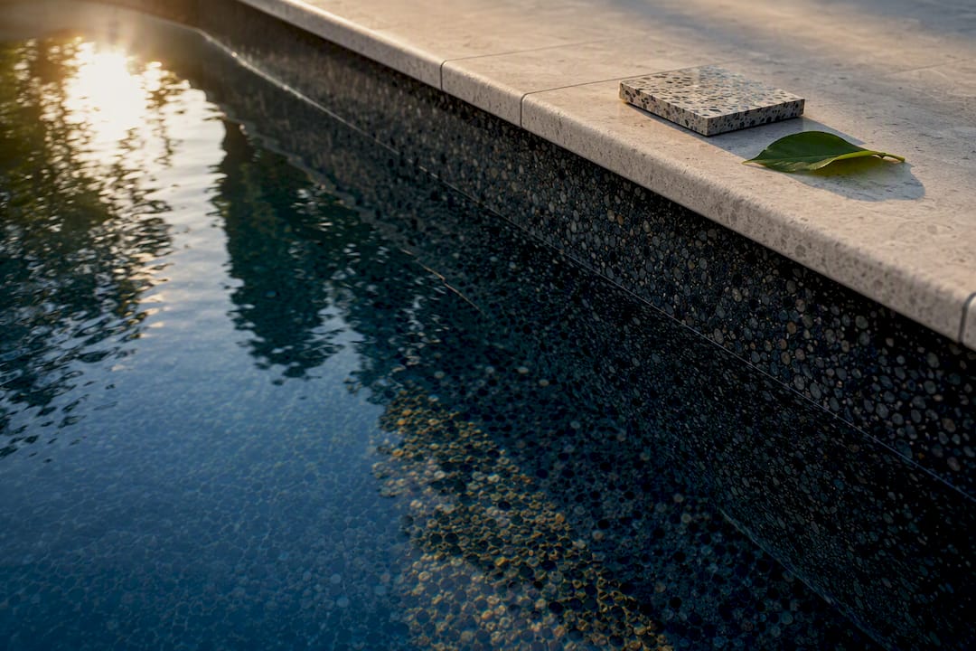 Dark pool finish beside pale stone decking