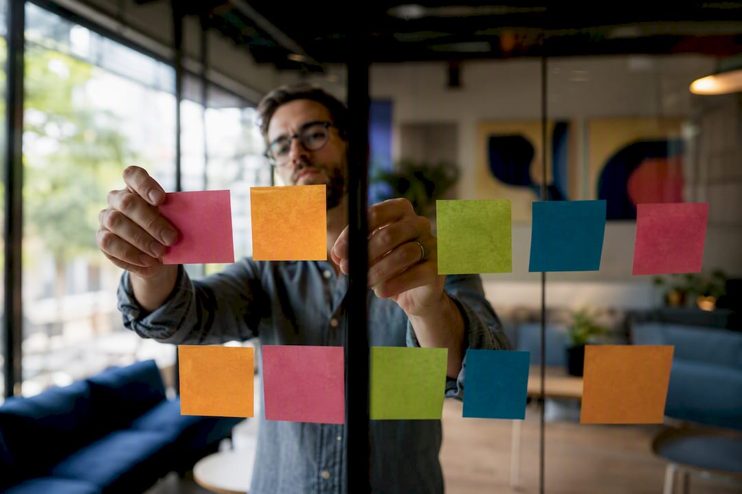 Hands arranging sticky notes on whiteboard