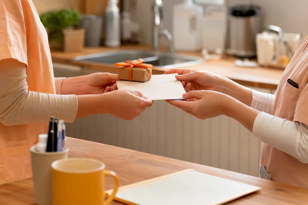 Caregiver hands exchanging a thank-you card